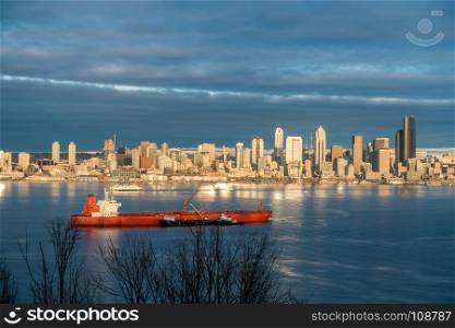 Skyscrapers in Seattle reflect the sun as a ship moves across Elliott Bay.