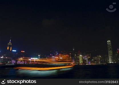 Skyscrapers lit up at night in a city, Victoria Harbor, Hong Kong Island, Hong Kong, China