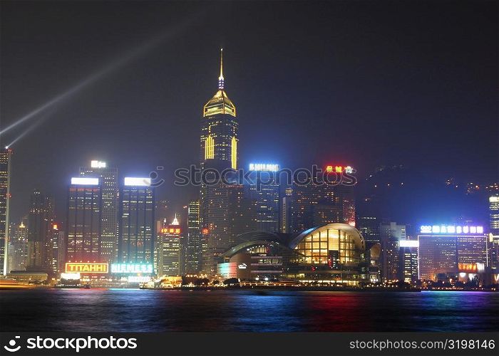 Skyscrapers lit up at night in a city, Victoria Harbor, Hong Kong Island, Hong Kong, China