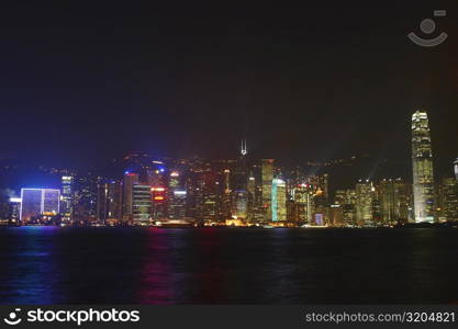 Skyscrapers lit up at night in a city, Victoria Harbor, Hong Kong Island, Hong Kong, China