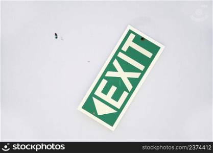 Slanted green emergency exit sign on the wall