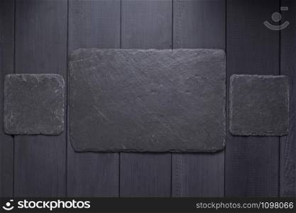 slate stone nameplate or wall sign at black wooden background texture surface, with screws