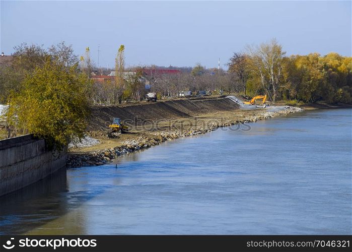 Slavyansk-na-Kubani, Russia - September 9, 2016: Works to strengthen Berek river. Usypanie gravel banks of the river with an excavator.. Works to strengthen Berek river. Usypanie gravel banks of the ri
