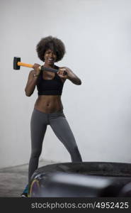 Sledgehammer Tire Hits african american woman workout at gym with hammer and tractor tire