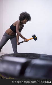 Sledgehammer Tire Hits african american woman workout at gym with hammer and tractor tire