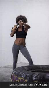 Sledgehammer Tire Hits african american woman workout at gym with hammer and tractor tire