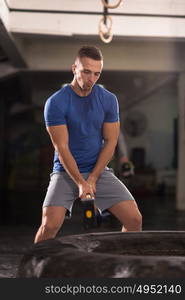 Sledgehammer Tire Hits young muscular man workout at gym with hammer and tractor tire