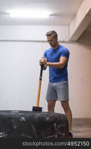 Sledgehammer Tire Hits young muscular man workout at gym with hammer and tractor tire