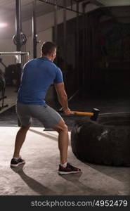 Sledgehammer Tire Hits young muscular man workout at gym with hammer and tractor tire