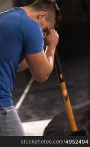 Sledgehammer Tire Hits young muscular man workout at gym with hammer and tractor tire