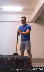 Sledgehammer Tire Hits young muscular man workout at gym with hammer and tractor tire