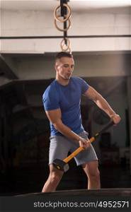 Sledgehammer Tire Hits young muscular man workout at gym with hammer and tractor tire