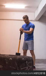 Sledgehammer Tire Hits young muscular man workout at gym with hammer and tractor tire