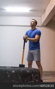 Sledgehammer Tire Hits young muscular man workout at gym with hammer and tractor tire