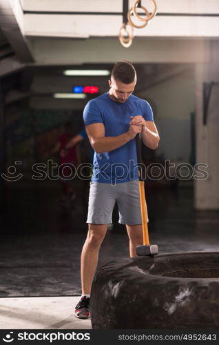 Sledgehammer Tire Hits young muscular man workout at gym with hammer and tractor tire