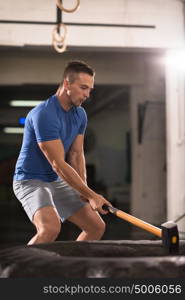 Sledgehammer Tire Hits young muscular man workout at gym with hammer and tractor tire