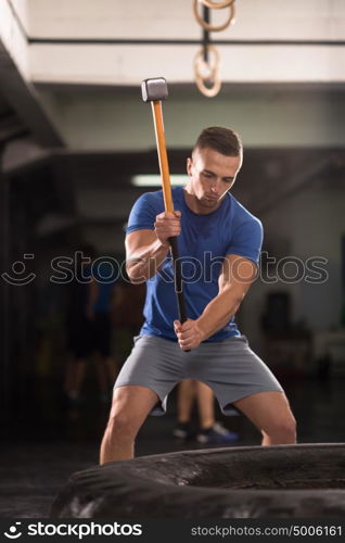 Sledgehammer Tire Hits young muscular man workout at gym with hammer and tractor tire