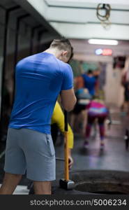 Sledgehammer Tire Hits young muscular man workout at gym with hammer and tractor tire