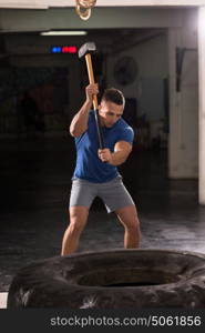 Sledgehammer Tire Hits young muscular man workout at gym with hammer and tractor tire