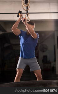 Sledgehammer Tire Hits young muscular man workout at gym with hammer and tractor tire