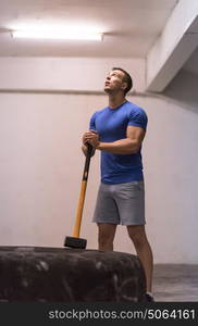 Sledgehammer Tire Hits young muscular man workout at gym with hammer and tractor tire