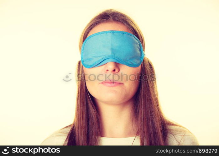 Sleep equipment concept. Portrait of brunette woman sleeping in blue eye mask. Studio shot on beige background. Brunette woman sleeping in blue eye sleep mask