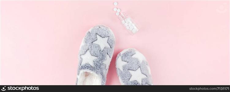 Sleep. Fluffy slippers, bottle with pills on pink background. Creative conceptual top view flat lay minimal style. Rest, good night, insomnia, relaxation, tired concept