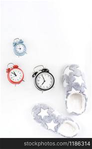 Sleep. Soft fluffy slippers and set of alarm clocks isolated on white background. Creative conceptual top view flat lay in minimal style. Rest, good night, insomnia, relaxation, tired, hygge concept