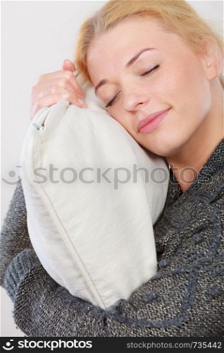 Sleep time, warm bedding, tiredness concept. Happy sleepy tired woman smiling and holding cozy white pillow. Happy sleepy woman holding cozy pillow