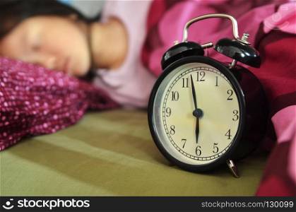 Sleeping child in bed and an alarm clock
