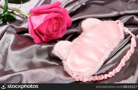  sleeping mask on a silk bedding sheet and pink rose, romantic evening concept, dating and love, relationship.  sleeping mask on a silk bedding sheet and pink rose, romantic evening concept, dating and love, relationship.