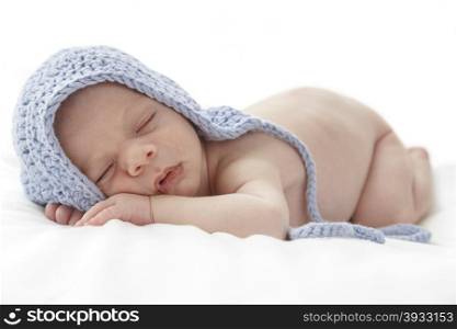 Sleeping newborn baby wearing a blue hat.