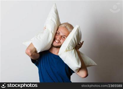 Sleeping well concept. Happy young man rested after good night sleep playing with pillows, smiling having fun. Man playing with pillows, good sleep concept