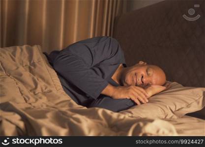 Sleepy old elderly black man yawning. African American people lying and sleeping on bed in bedroom at late night at home. Lifestyle