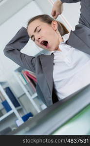 sleepy young business woman sitting at office desk
