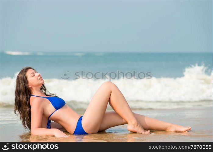slender and beautiful woman posing on a background of the sea waves