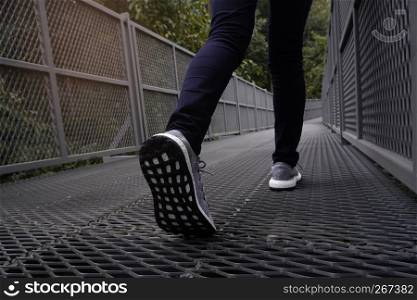 Slender female legs in blue jeans and grey sneakers walking along forest trail