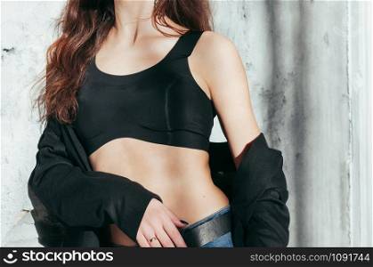 Slender fit girl in a black jacket and bra, fashion style. Perfect skin tone, long nut-brown hair. Concept for clothes or fashion catalog or magazine cover