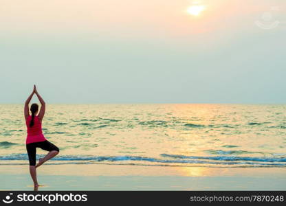 slender girl balancing on one leg. Yoga on the beach