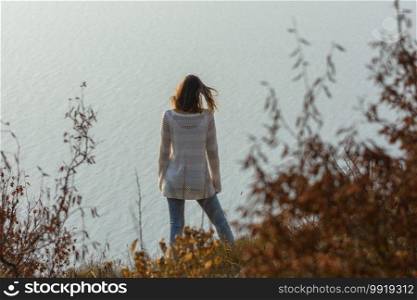Slender girl standing on the seashore, rear view