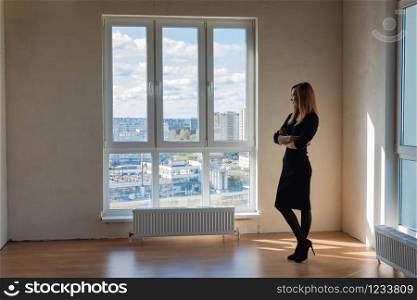 Slender girl stands at a large stained glass window in an empty room