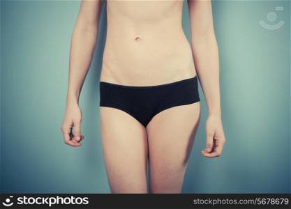 Slender woman with toned stomach is wearing black underwear
