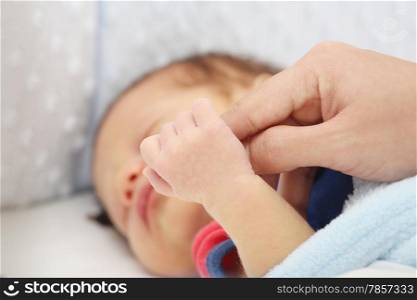 Slept baby hand holding mother finger