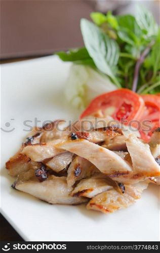 slice grilled pork served with fresh vegetable on white dish. grilled pork