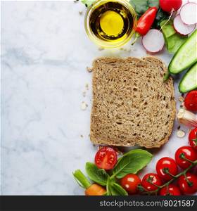 Slice of a whole wheat bread and healthy organic vegetables for making sandwiches. Healthy eating or cooking concept. Background layout with free text space.