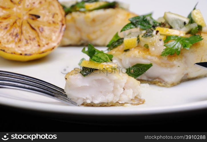 slice of baked fish perch with herbs and lemon slices