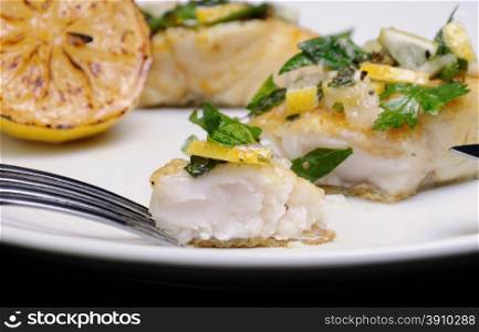 slice of baked fish perch with herbs and lemon slices