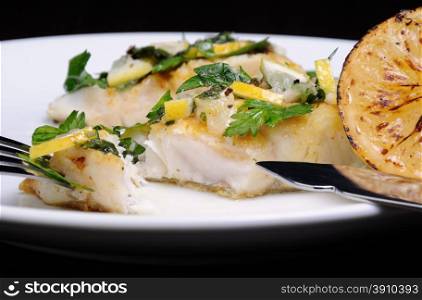 slice of baked fish perch with herbs and lemon slices