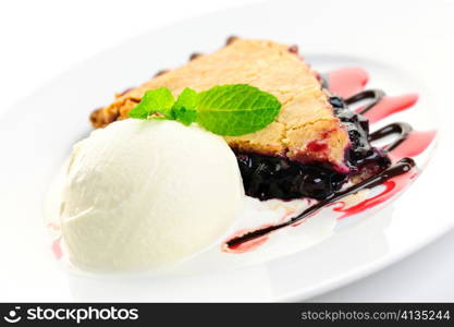 Slice of blueberry pie and vanilla ice cream served with dessert sauces