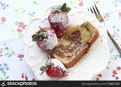 slice of cake with fresh strawberries dusted with powdered sugar on a vintage floral fabric background